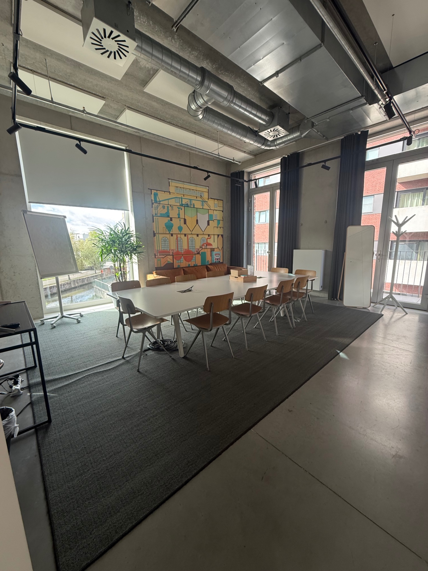 Bright classroom at De Hoorn in Leuven with a hand-painted mural, whiteboard and canal view