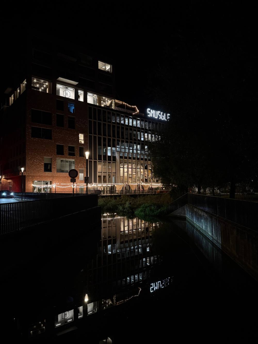 Historic De Hoorn brewery building illuminated at night in Leuven
